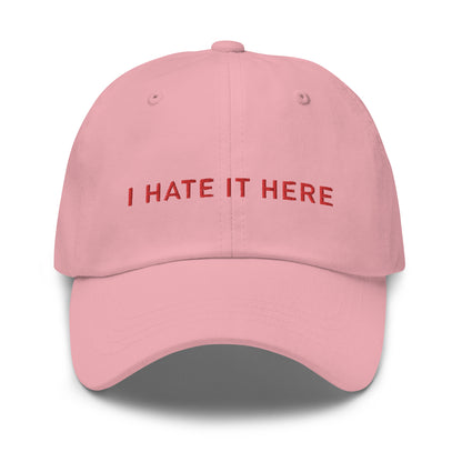 Bild eines Baseball-Caps mit dem Spruch 'I HATE IT HERE' auf weißem Hintergrund. Ein humorvolles Accessoire für diejenigen, die lieber zuhause bleiben. Hergestellt aus Baumwoll-Chino-Cord.